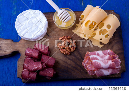 Cheese and meat plate with walnuts on blue wooden Cheese and meat plate with walnuts on blue wooden 33565618