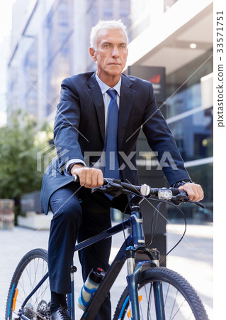 Successful businessman riding bicycle Successful businessman riding bicycle 33571751