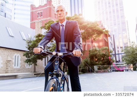 Successful businessman riding bicycle Successful businessman riding bicycle 33572074