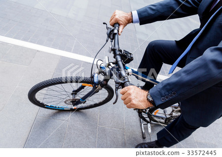 Successful businessman riding bicycle Successful businessman riding bicycle 33572445