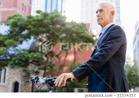 Successful businessman riding bicycle Successful businessman riding bicycle 33574357