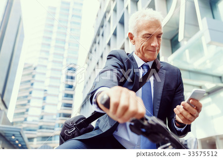 Successful businessman riding bicycle Successful businessman riding bicycle 33575512