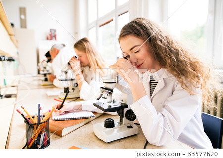 Beautiful high school students with microscopes in 33577620
