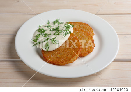 Draniki with sour cream on wooden table Draniki with sour cream on wooden table 33581600