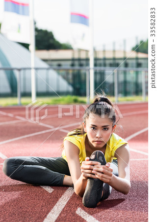 woman athlete stretching on racing track before woman athlete stretching on racing track before 33582833