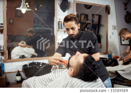 Hairstylist in black combing out bread for brunet 33584569