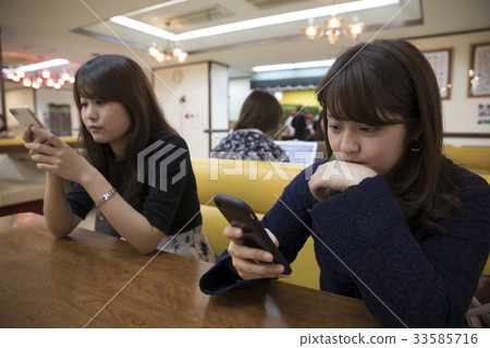 Female college student operating a smartphone with family 33585716