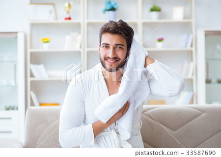 Young man in a bathrobe after shower drying hair 33587690