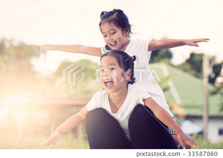 Two asian girls having fun to fly on mother's leg Two asian girls having fun to fly on mother's leg 33587860