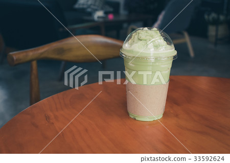 Iced Matcha latte tea on wooden table. Iced Matcha latte tea on wooden table. 33592624