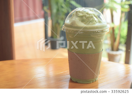 Iced Matcha latte tea on wooden table. Iced Matcha latte tea on wooden table. 33592625