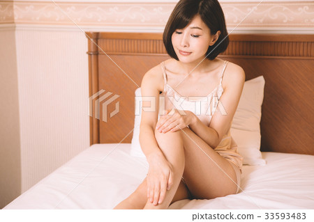 Woman doing skin care for legs in bed Woman doing skin care for legs in bed 33593483