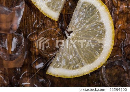 ice cube and sliced lemon on wooden table, top ice cube and sliced lemon on wooden table, top 33594300