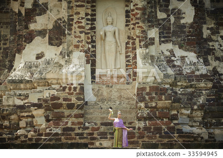 A Thai woman is dancing under a statue 33594945