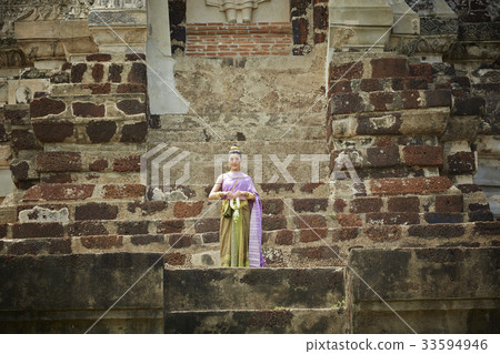 A Thai woman is standing on a stair of a temple 33594946