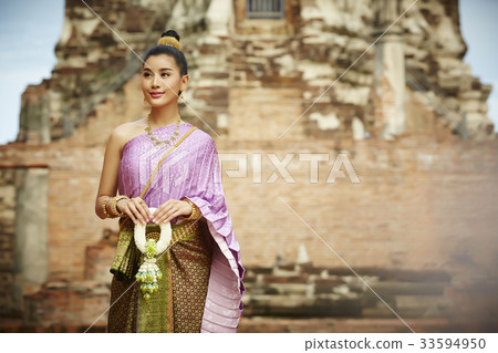 A picture of a beautiful girl holding a garland near a temple 33594950