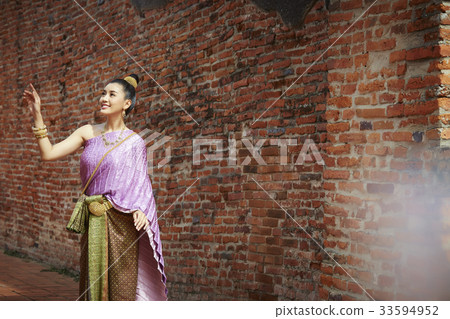 A picture of a Thai woman with a smile posing near a brick wall 33594952
