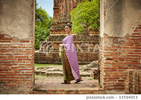 A Thai woman in traditional costume is walking in a temple 33594953