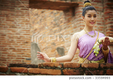 a Thai woman is holding a garland and smiling in old temple 33594993