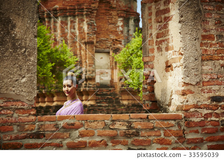 a young woman is standing in historical park and looking at the camera 33595039