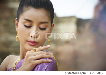 a thai model is dressed in traditional costume and posing outdoors 33595042