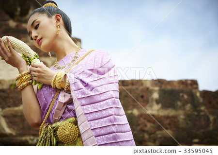 thai woman is standing in historical park while looking flower garland on her hands 33595045