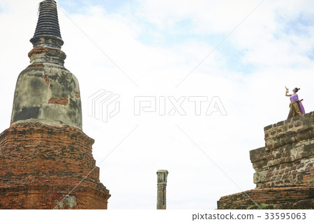 thai female dancer is performing next to stone wall 33595063