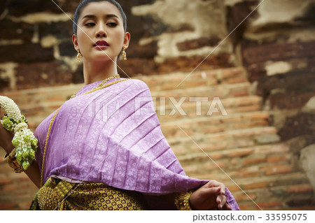thai woman is standing and looking down outdoors 33595075