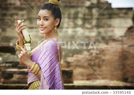 A woman in Thai costume is holding a garland and smiling 33595148