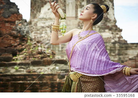 A Thai girl is holding a garland and looking at above 33595168