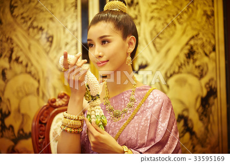 A Thai woman is holding a garland and smiling 33595169