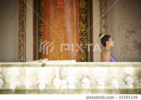 The picture of a Thai girl standing near the wall of a pagoda The picture of a Thai girl standing near the wall of a pagoda 33595199