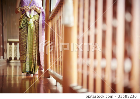 A Thai woman is holding the Thai ornament while standing on the balcony. A Thai woman is holding the Thai ornament while standing on the balcony. 33595236