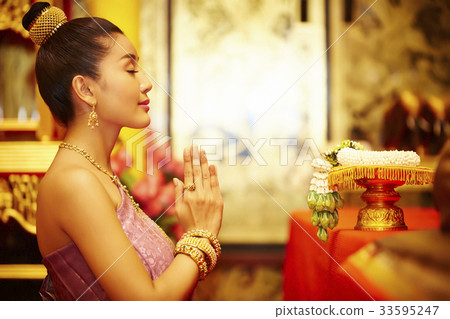 A Thai young woman is praying in front of the Thai ornament. 33595247