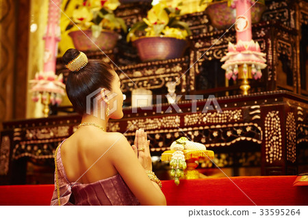 A portrait of beautiful Thai woman genuflecting and praying in front of the altar. 33595264