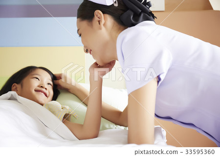 A nurse is talking cheerfully to a kid patient A nurse is talking cheerfully to a kid patient 33595360