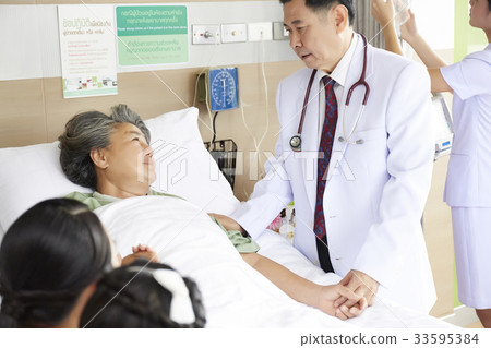 a doctor is talking to elderly woman who is lying in bed in clinic 33595384