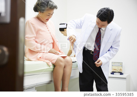 Doctor is checking up elderly woman's leg with his hummer Doctor is checking up elderly woman's leg with his hummer 33595385