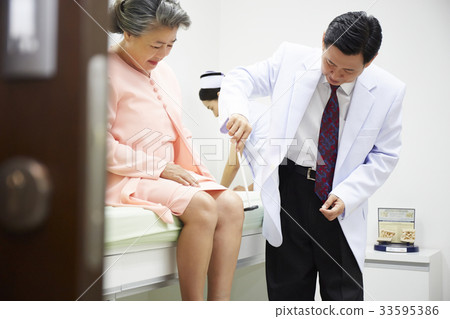 a doctor is checking elderly woman's knee jerk in clinic a doctor is checking elderly woman's knee jerk in clinic 33595386