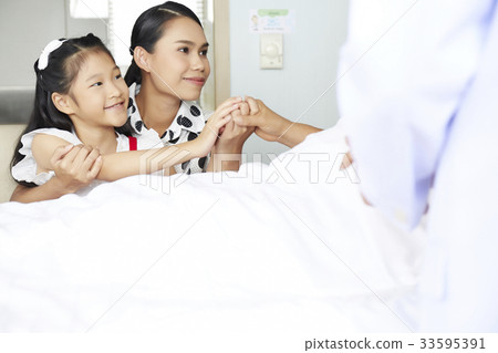 mother and daughter are holding someone's hand who is lying in bed 33595391