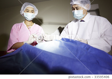 a doctor and nurse are carrying out an operation 33595406