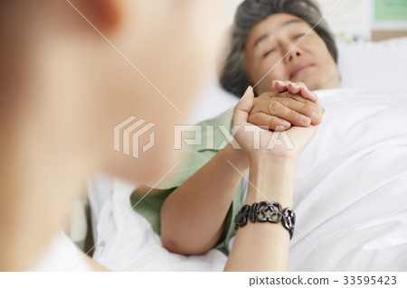 elderly woman is lying down in bed and holding someone's hand 33595423