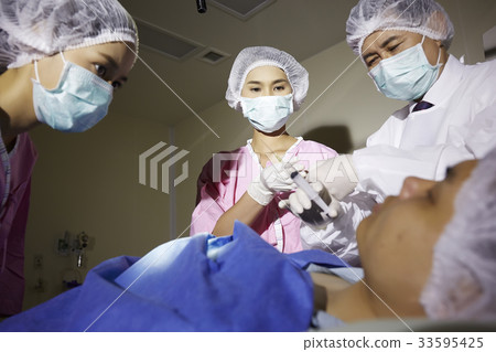 three surgeons are performing surgery in operating room three surgeons are performing surgery in operating room 33595425