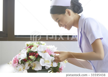 young female nurse is arranging flower and smiling in hospital 33595438