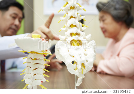 The doctor is pointing the bone model to the old patient The doctor is pointing the bone model to the old patient 33595482
