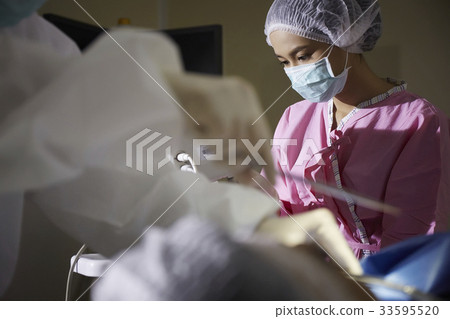 A nurse and a doctor are doing surgeon in surgeon room 33595520