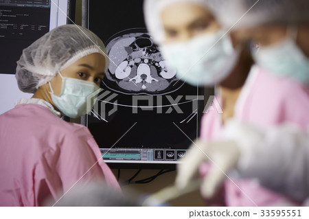 The picture of a nurse standing next to mri and looking her colleagues operating 33595551