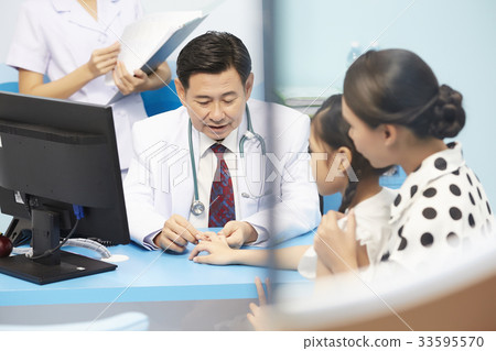 A photo of an Asian doctor looking patient 's fingers in clinic. A photo of an Asian doctor looking patient 's fingers in clinic. 33595570