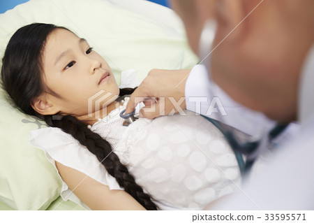 A little girl is lying while the doctor is doing a physical examination. A little girl is lying while the doctor is doing a physical examination. 33595571