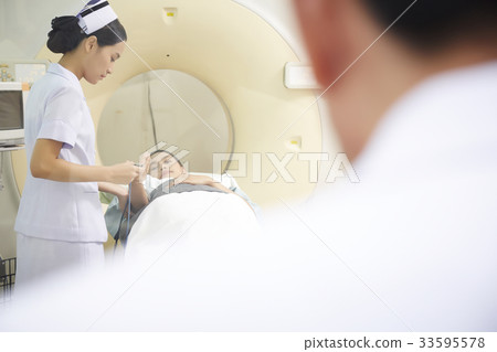 The doctor is looking while the young nurse helping her patient. 33595578